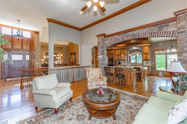26650 W 100th Pl, Olathe, KS 66061 - living room with arched walkways, wood finished floors, ornamental molding, ceiling fan, and a towering ceiling