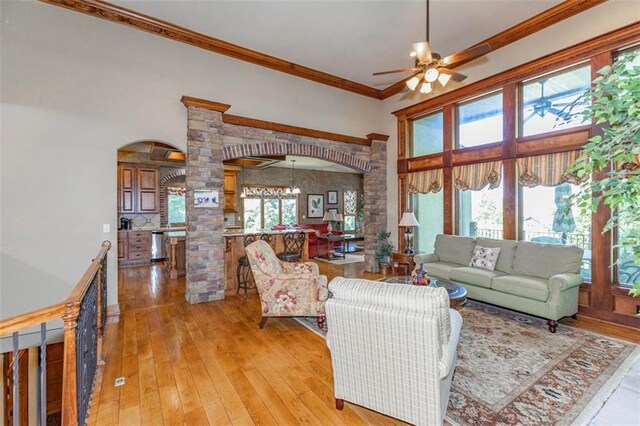 26650 W 100th Pl, Olathe, KS 66061 - living room with arched walkways, decorative columns, a ceiling fan, ornamental molding, and light wood-style floors