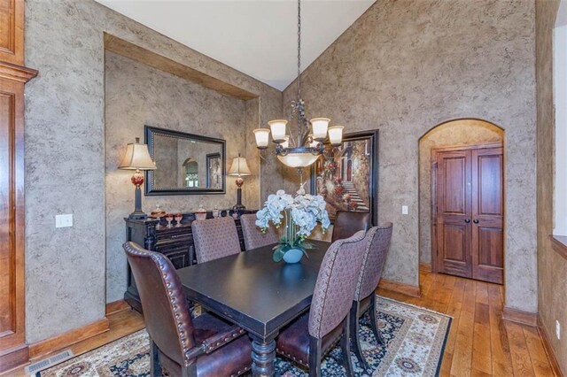 26650 W 100th Pl, Olathe, KS 66061 - dining area featuring a chandelier, wood-type flooring, high vaulted ceiling, and baseboards