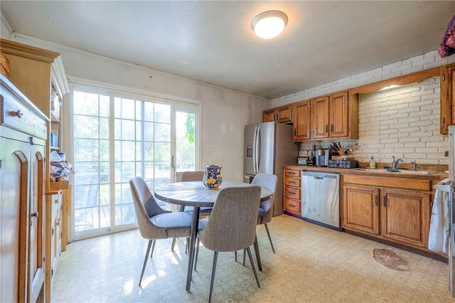 205 N 82nd Ter, Kansas City, KS 66112 - kitchen featuring stainless steel dishwasher, a sink, light floors, and brown cabinets