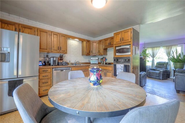 205 N 82nd Ter, Kansas City, KS 66112 - kitchen featuring stainless steel appliances, brown cabinetry, decorative backsplash, and a sink
