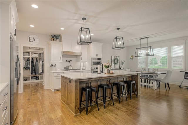 2241 Foxtail Dr, Kearney, MO 64060 - kitchen featuring light countertops, a kitchen bar, light wood finished floors, a kitchen island with sink, and recessed lighting