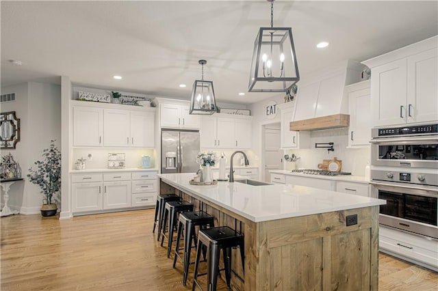 2241 Foxtail Dr, Kearney, MO 64060 - kitchen featuring appliances with stainless steel finishes, a sink, custom exhaust hood, a breakfast bar area, and a center island with sink