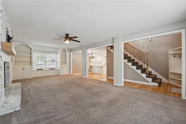 15642 W 146th Ter, Olathe, KS 66062 - unfurnished living room featuring carpet, ceiling fan, a chandelier, a fireplace with raised hearth, and stairs