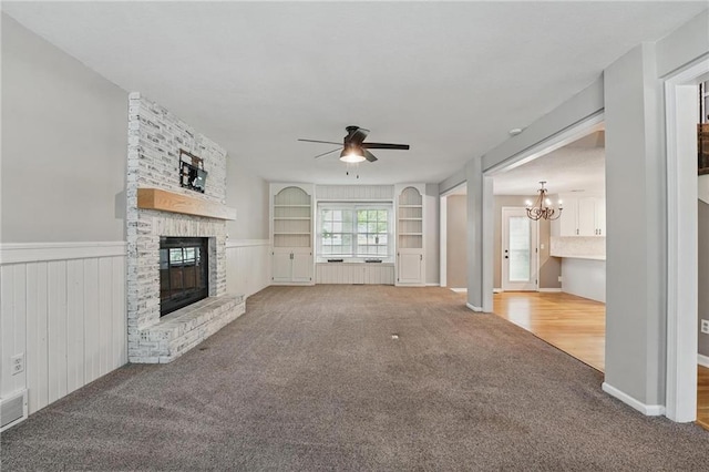 15642 W 146th Ter, Olathe, KS 66062 - unfurnished living room featuring a fireplace, carpet, a chandelier, ceiling fan, and a wainscoted wall