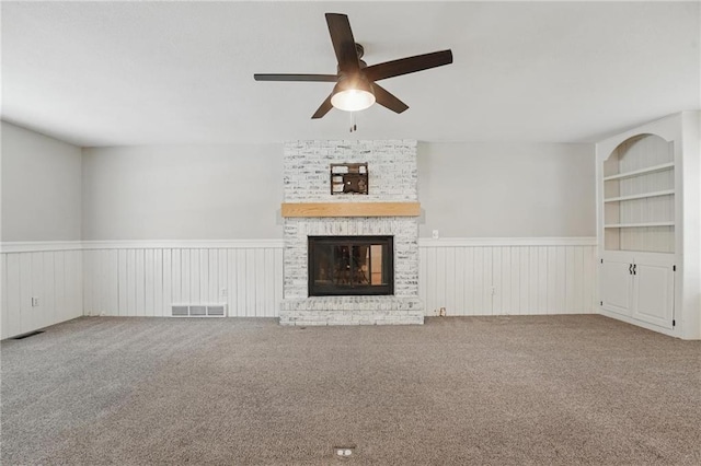 15642 W 146th Ter, Olathe, KS 66062 - unfurnished living room with wainscoting, a ceiling fan, carpet, and a brick fireplace