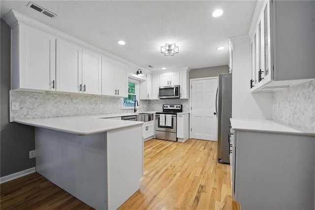 15642 W 146th Ter, Olathe, KS 66062 - kitchen with stainless steel appliances, a peninsula, light wood finished floors, white cabinets, and recessed lighting
