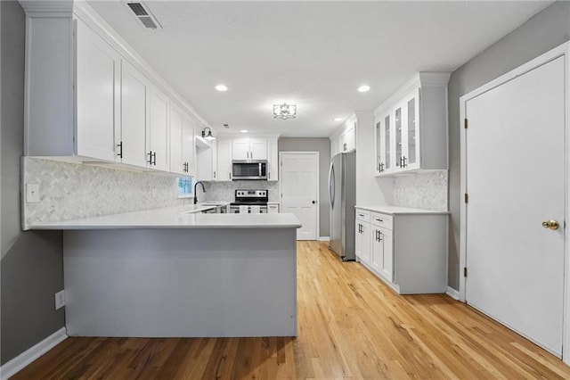 15642 W 146th Ter, Olathe, KS 66062 - kitchen with appliances with stainless steel finishes, a sink, a peninsula, decorative backsplash, and glass insert cabinets