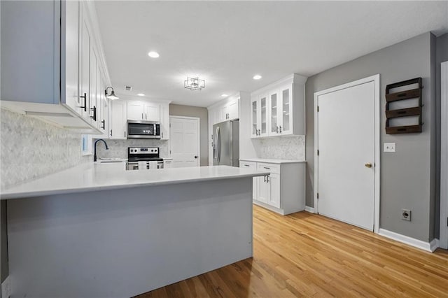 15642 W 146th Ter, Olathe, KS 66062 - kitchen featuring stainless steel appliances, light wood-style floors, a peninsula, glass insert cabinets, and decorative backsplash