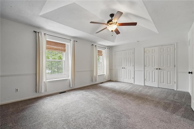 15642 W 146th Ter, Olathe, KS 66062 - unfurnished bedroom with multiple closets, carpet flooring, ceiling fan, baseboards, and a tray ceiling