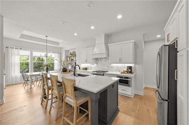 11573 S Mize Rd, Olathe, KS 66061 - kitchen with stainless steel appliances, premium range hood, a sink, decorative backsplash, and light countertops