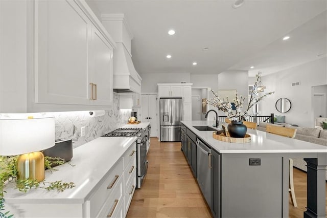 11573 S Mize Rd, Olathe, KS 66061 - kitchen with appliances with stainless steel finishes, a sink, light wood-style floors, white cabinetry, and a breakfast bar area