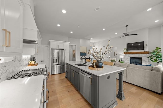 11573 S Mize Rd, Olathe, KS 66061 - kitchen with stainless steel appliances, a sink, white cabinetry, a ceiling fan, and light wood-style flooring
