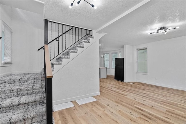 527 Cypress Ave, Kansas City, MO 64124 - stairs with a textured ceiling, wood finished floors, and baseboards
