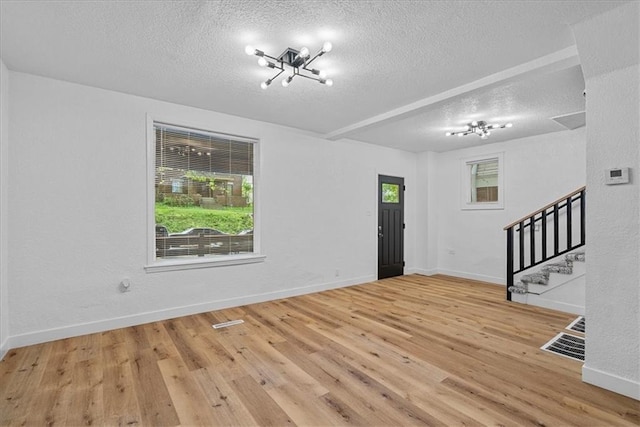 527 Cypress Ave, Kansas City, MO 64124 - unfurnished living room with a textured ceiling, stairs, wood finished floors, a chandelier, and baseboards