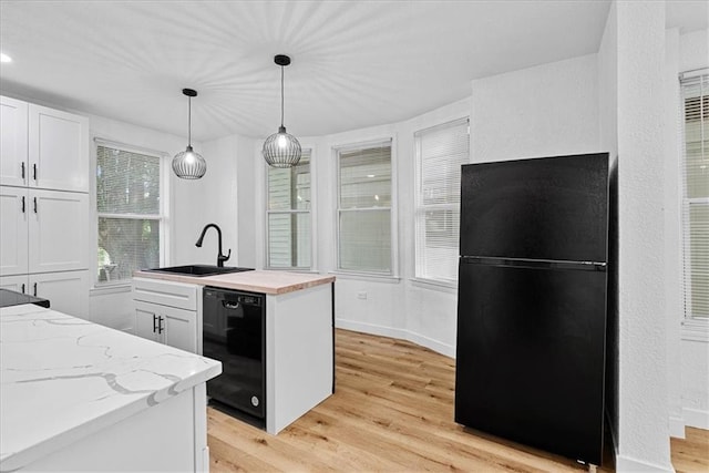 527 Cypress Ave, Kansas City, MO 64124 - kitchen featuring black appliances, a sink, white cabinets, light wood finished floors, and hanging light fixtures