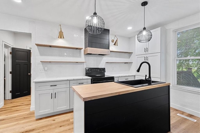527 Cypress Ave, Kansas City, MO 64124 - kitchen featuring black range with electric cooktop, open shelves, wood counters, a sink, and light wood finished floors