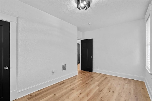 527 Cypress Ave, Kansas City, MO 64124 - empty room featuring light wood-type flooring, baseboards, and a textured ceiling