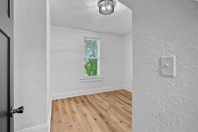527 Cypress Ave, Kansas City, MO 64124 - unfurnished room with a textured ceiling, wood finished floors, a textured wall, and baseboards