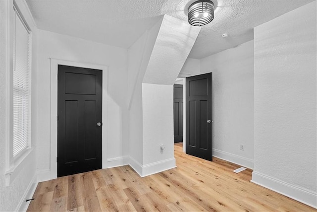 527 Cypress Ave, Kansas City, MO 64124 - unfurnished bedroom featuring light wood-style flooring, a textured ceiling, and baseboards