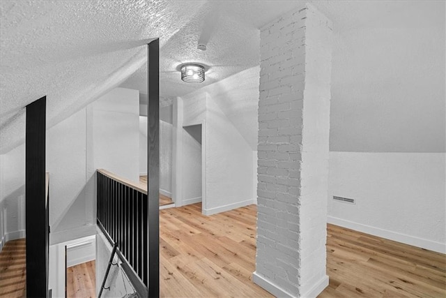 527 Cypress Ave, Kansas City, MO 64124 - additional living space featuring wood finished floors, lofted ceiling, a textured ceiling, and baseboards