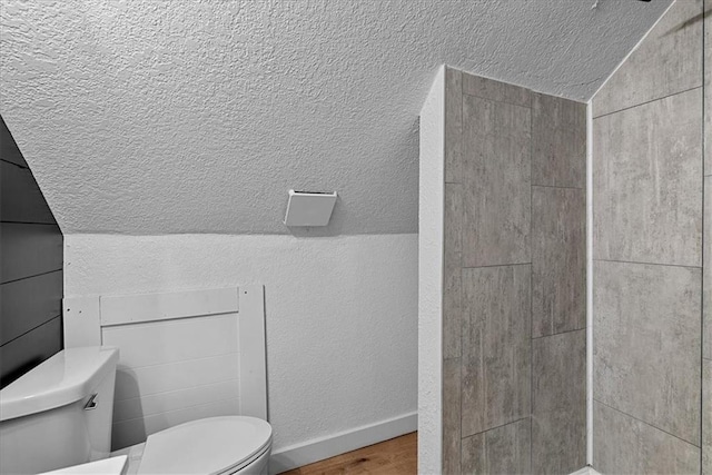 527 Cypress Ave, Kansas City, MO 64124 - bathroom featuring toilet, wood finished floors, a textured ceiling, tiled shower, and baseboards
