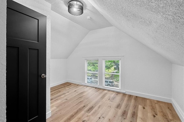 527 Cypress Ave, Kansas City, MO 64124 - additional living space featuring wood finished floors, baseboards, a textured ceiling, and vaulted ceiling