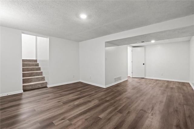 8003 E 118th Ter, Kansas City, MO 64134 - finished below grade area featuring a textured ceiling, dark wood finished floors, stairway, baseboards, and recessed lighting