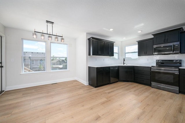 1012 2nd St, Perry, KS 66073 - kitchen with stainless steel appliances, light wood finished floors, light countertops, dark cabinets, and recessed lighting