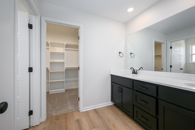 1012 2nd St, Perry, KS 66073 - bathroom featuring wood finished floors, a walk in closet, double vanity, baseboards, and recessed lighting