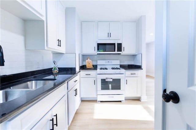 3312 Delavan Ave, Kansas City, KS 66104 - kitchen featuring gas range gas stove, a sink, tasteful backsplash, white cabinetry, and light wood-style floors