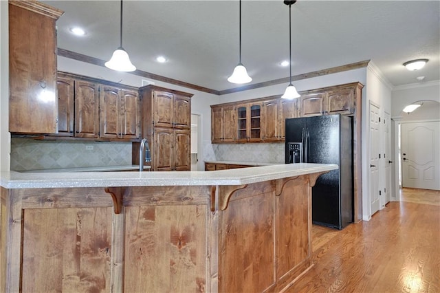 4641 SW Soldier Dr, Lees Summit, MO 64082 - kitchen with black fridge, ornamental molding, a breakfast bar area, a peninsula, and light countertops