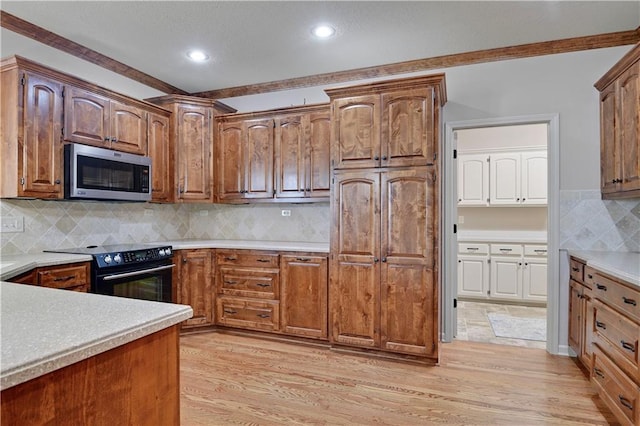4641 SW Soldier Dr, Lees Summit, MO 64082 - kitchen with stainless steel microwave, black electric range oven, backsplash, light wood-style flooring, and recessed lighting