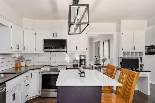 5208 NW 58th Ter, Kansas City, MO 64151 - kitchen featuring appliances with stainless steel finishes, white cabinets, backsplash, dark wood-style floors, and a kitchen island