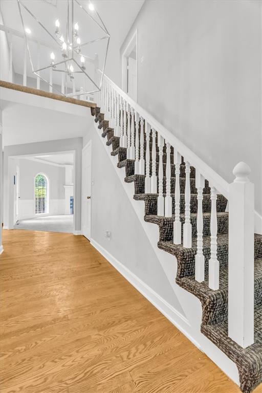 1600 NE 97th St, Kansas City, MO 64155 - stairs featuring wood finished floors, baseboards, and a chandelier