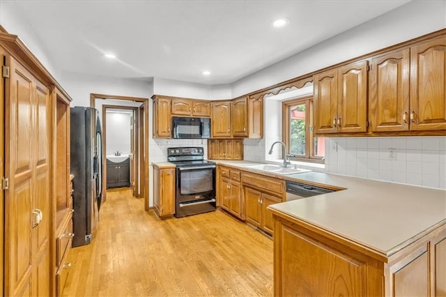 1600 NE 97th St, Kansas City, MO 64155 - kitchen with stainless steel appliances, a sink, a peninsula, brown cabinetry, and light wood finished floors