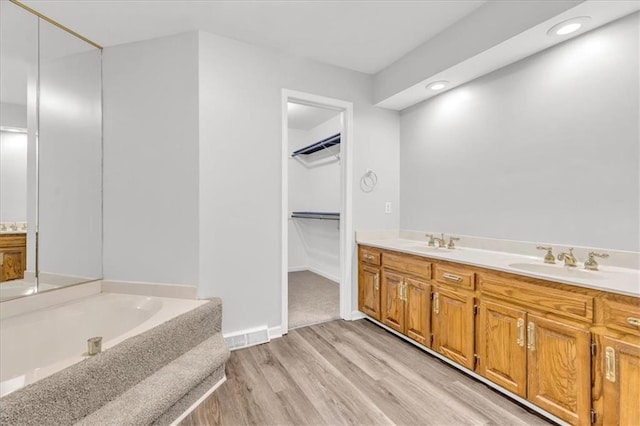 1600 NE 97th St, Kansas City, MO 64155 - full bathroom with wood finished floors, a bath, double vanity, a spacious closet, and recessed lighting
