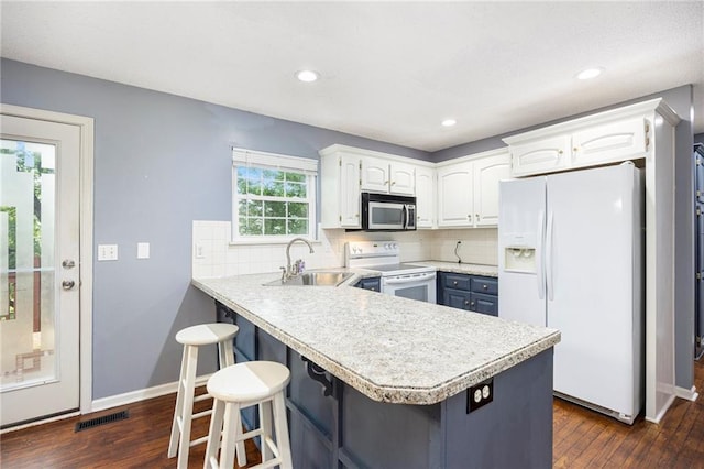 417 N Locust St, Gardner, KS 66030 - kitchen featuring white appliances, dark wood-type flooring, a peninsula, tasteful backsplash, and white cabinets