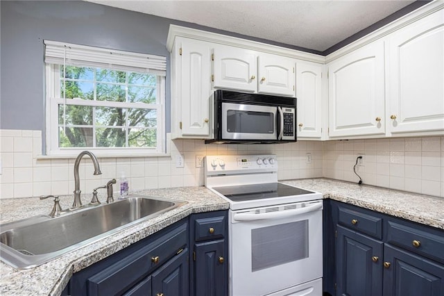 417 N Locust St, Gardner, KS 66030 - kitchen with white electric range oven, stainless steel microwave, blue cabinetry, white cabinetry, and a textured ceiling