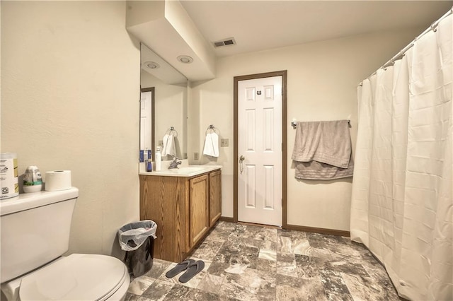 bathroom with toilet, vanity, and baseboards
