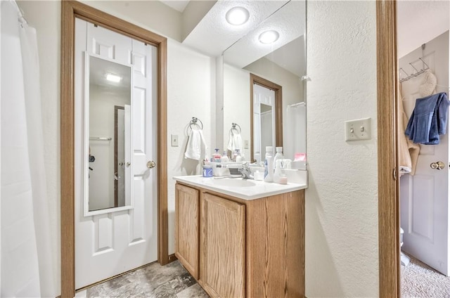 full bath with a textured wall and vanity