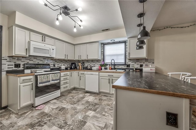 kitchen featuring white appliances, a peninsula, a sink, backsplash, and a textured ceiling