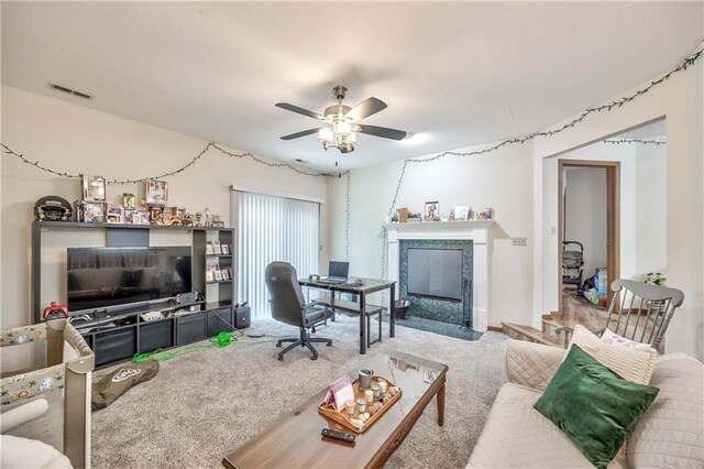 carpeted living area with ceiling fan and a premium fireplace
