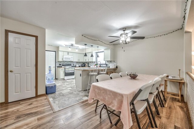 dining space with light wood finished floors and a ceiling fan