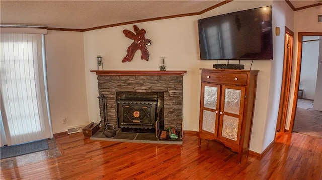 20435 Rb Hwy, Flemington, MO 65650 - unfurnished living room with wood finished floors, ornamental molding, a stone fireplace, and a textured ceiling