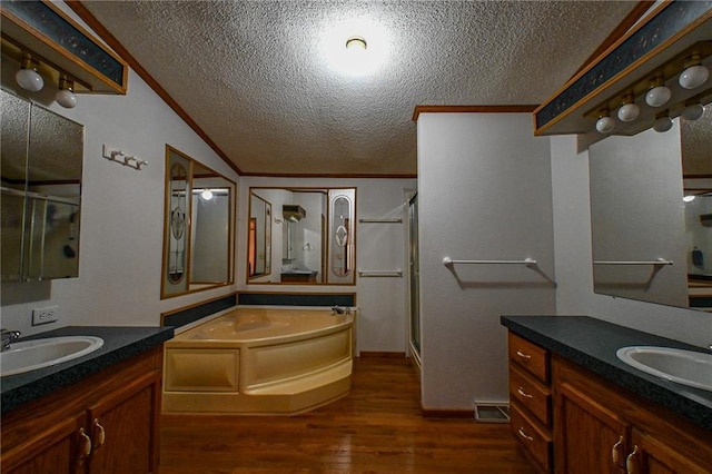 20435 Rb Hwy, Flemington, MO 65650 - full bathroom featuring a textured ceiling, a stall shower, wood finished floors, a garden tub, and two vanities