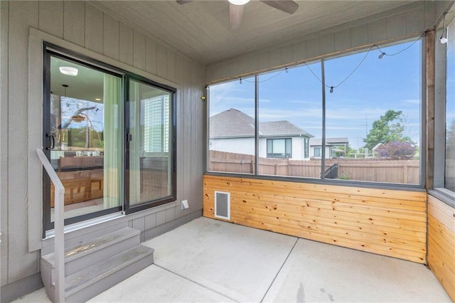 301 Sunrise Dr, Louisburg, KS 66053 - unfurnished sunroom featuring a ceiling fan, wooden walls, and concrete floors