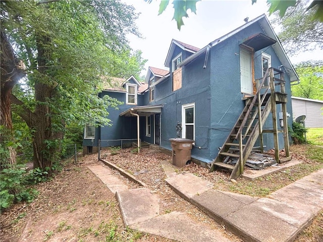 back of property featuring stucco siding and stairs