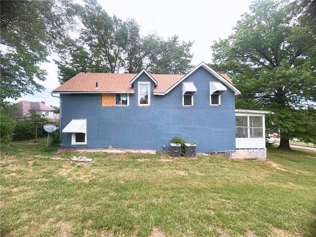 view of side of property with a yard, a sunroom, roof with shingles, and central AC