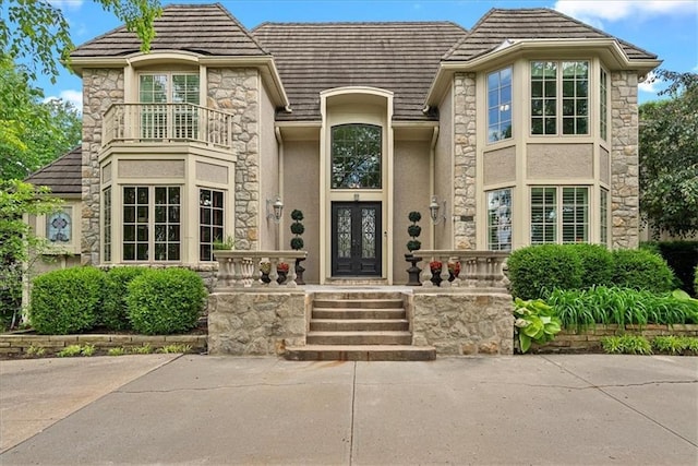 12613 Sherwood St, Leawood, KS 66209 - property entrance featuring french doors, stucco siding, stone siding, a balcony, and a tiled roof